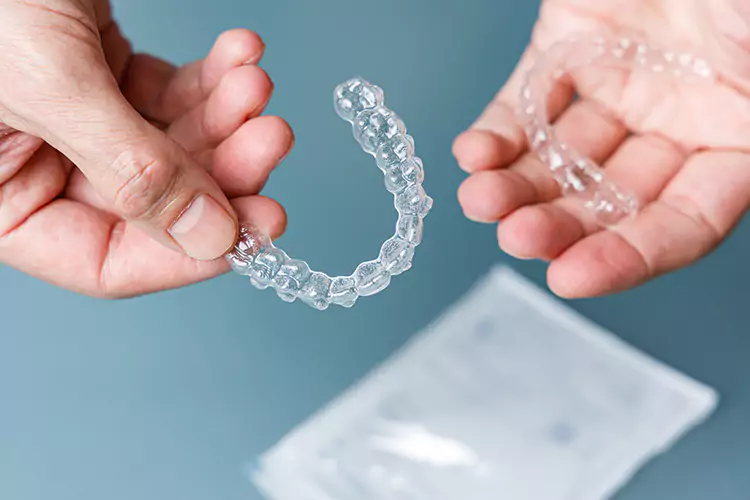 Hands holding Invisalign clear aligners