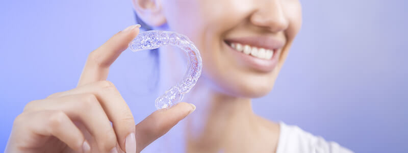 Smiling woman holding Invisalign