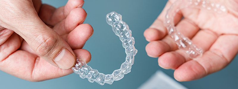 Hands holding Invisalign clear aligners
