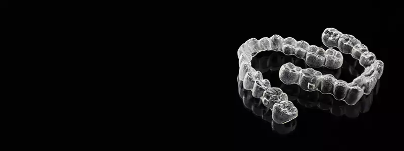 Invisalign clear aligners on a reflective black surface